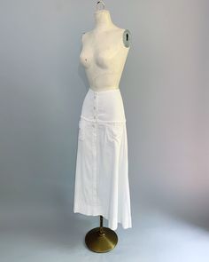 "Very special antique ribbed white cotton skirt circa 1900s to early 1920s. I've seen these referred to as both tennis and walking skirts. The skirt has pearly buttons but actually fastens with little snaps and also has front pockets. Excellent vintage condition. There is an area of very faint discoloration on the front bottom as shown in the close-up photo. Measurements: Waist - 24\" Hips - 35\" Length - 35\"" White Buttoned Skirt For Daywear, Classic White Skirt With Pockets, Vintage White Pleated Skirt, Vintage White Lined Skirt, White Victorian Skirt, Vintage White Gathered Skirt Bottoms, Striped Edwardian Skirt, Vintage Beige Cotton Skirt, Walking Skirt