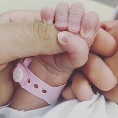 a close up of a person holding a baby's hand