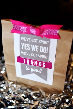 a brown paper bag with a pink bow on it and some tinsel around it