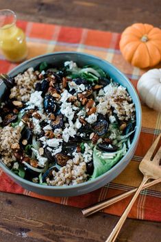 a bowl filled with food sitting on top of a table next to two pumpkins