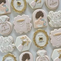 decorated cookies are arranged in rows on a white tablecloth with gold trimmings