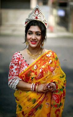 a woman in a yellow and red sari with a tiara on her head