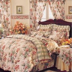 a bed room with a neatly made bed and flowers on the comforter, pillows and curtains