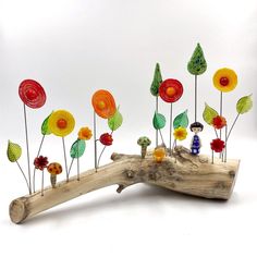 a group of colorful glass flowers sitting on top of a wooden branch