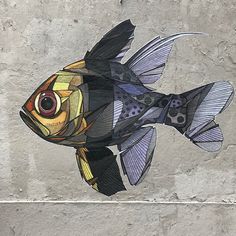 a fish made out of paper sitting on top of a wall