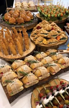 a table topped with lots of different types of sandwiches and appetizers on wooden trays