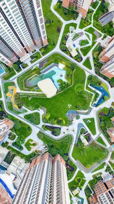 an aerial view of the city with lots of tall buildings and green grass in the middle