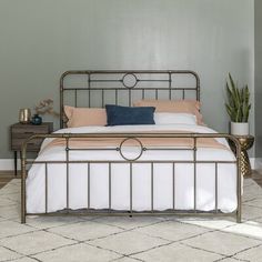 a bedroom with a metal bed frame and white linens on the floor next to a potted plant