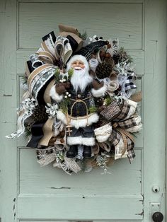 a christmas wreath with santa claus and pine cones hanging on the front door to decorate it