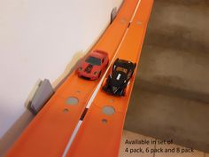 two toy cars on an orange track next to some stairs with instructions for how to set up them