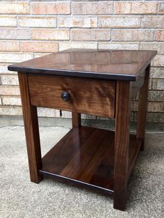 a small wooden table sitting on top of a cement floor next to a brick wall