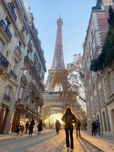 the eiffel tower is in the background as people walk down an alley way