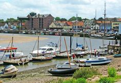 several boats are docked in the water near some houses and buildings on either side of the river