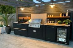 an outdoor kitchen with grill, sink and cabinets on the outside patio at night time