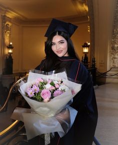 a woman in graduation gown holding a bouquet of flowers