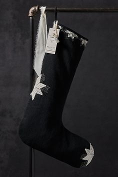 a black christmas stocking with white stars hanging on a metal pole in front of a dark background