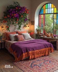 a bed with purple and orange sheets in front of a large stained glass window filled with potted plants