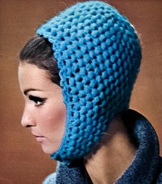 a woman wearing a blue crocheted hat with a scarf around her neck and hood on