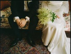 a bride and groom sitting on a couch with flowers in their lapel bouquets