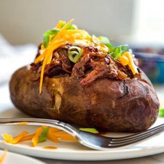 a close up of a baked potato on a plate with a fork next to it