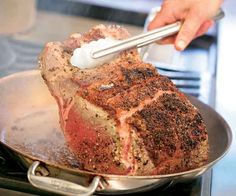 a person using a spatula to cut up a piece of meat on a pan