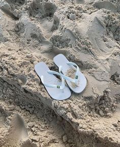 a pair of white flip flops sitting in the sand