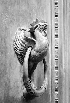 a black and white photo of a door handle with a rooster on it's side