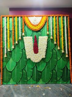 a green wall decorated with flowers and garlands