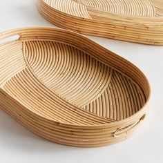 two oval bamboo trays sitting next to each other on top of a white surface