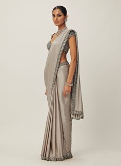 This exquisite Grey Crystal and Sequin Hand Embroidered Satin Saree Set is the perfect fusion of traditional elegance and modern sophistication. Made from luxurious satin and georgette, the grey saree features intricate hand embroidery with shimmering sequins and tonal crystal embellishments along the borders, offering a subtle yet opulent look. Paired with a cap-sleeved blouse adorned with sparkling crystal accents, jewelled design that adds a chic, contemporary twist. Ideal for Mehndi, Sangeet ceremonies, or as a statement saree at reception. Composition : Saree - Satin and Blouse - Georgette Care: Dry Clean Only and Vacuum Storage This product can be customized for sleeves, blouse length and neckline Delivery : 6-8 weeks as the product is hand crafted. Check Size Guide or choose MySize Saree Satin, Vani Vats, Grey Saree, Vacuum Storage, Indian Wedding Wear, Satin Saree, Sleeves Blouse, Crystal Embellishment, Blouse Length