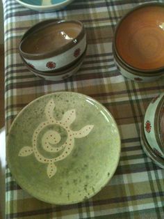 bowls and plates are sitting on a checkered tablecloth with an animal painted on the bowl