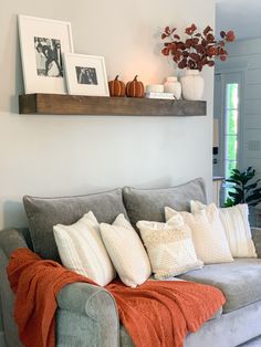 a couch with pillows and blankets on it in a living room next to a potted plant