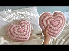 two crocheted heart cushions sitting on top of a bed