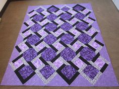 a purple and black quilt is laying on the floor