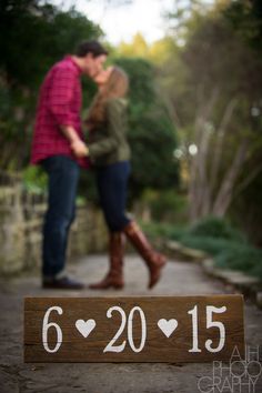 a man and woman standing next to each other in front of a wooden sign that reads 6 20