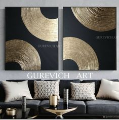 two gold and black paintings on the wall in a living room with couches, coffee table