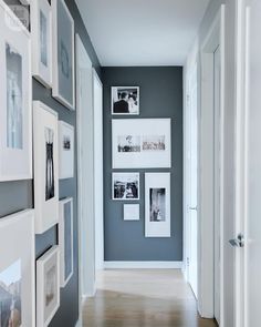 a long hallway with pictures on the wall and wood flooring in front of it