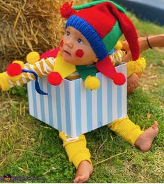 a small child wearing a clown costume sitting on the grass