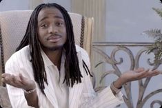 a man with dreadlocks sitting in a chair holding his hands out to the side