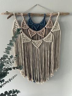 macrame wall hanging with blue and white crocheted fringes on a wooden stick