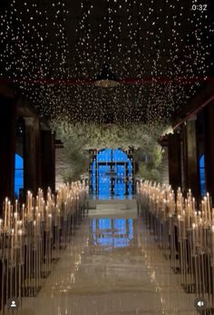 the inside of a building with rows of candles lit up in front of it and lights hanging from the ceiling