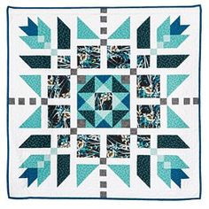 a blue and white quilt with an arrow design on the center, in front of a white background