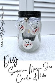 a glass jar filled with snowman magnets on top of a white table cloth