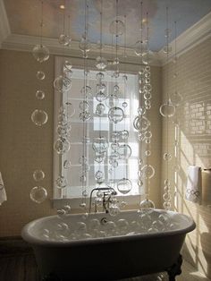 a bath tub sitting next to a window with bubbles hanging from it's ceiling