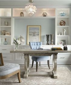 a blue chair sitting in front of a desk with bookshelves and vases on it