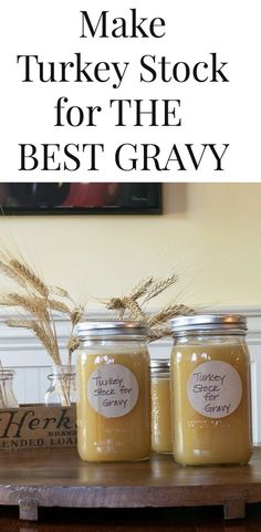 three jars filled with homemade turkey stock sitting on top of a wooden table next to a painting