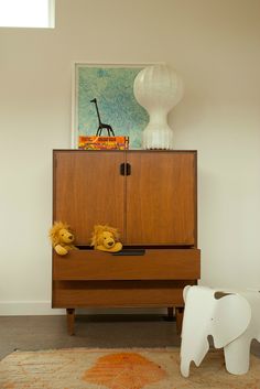 a wooden cabinet sitting next to a white elephant toy on top of a rug in a living room