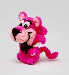 a crocheted pink and white stuffed animal on a white surface with its mouth open