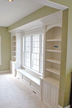 an empty living room with built in bookshelves