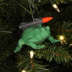 a green frog ornament hanging from a christmas tree with red and gray lights